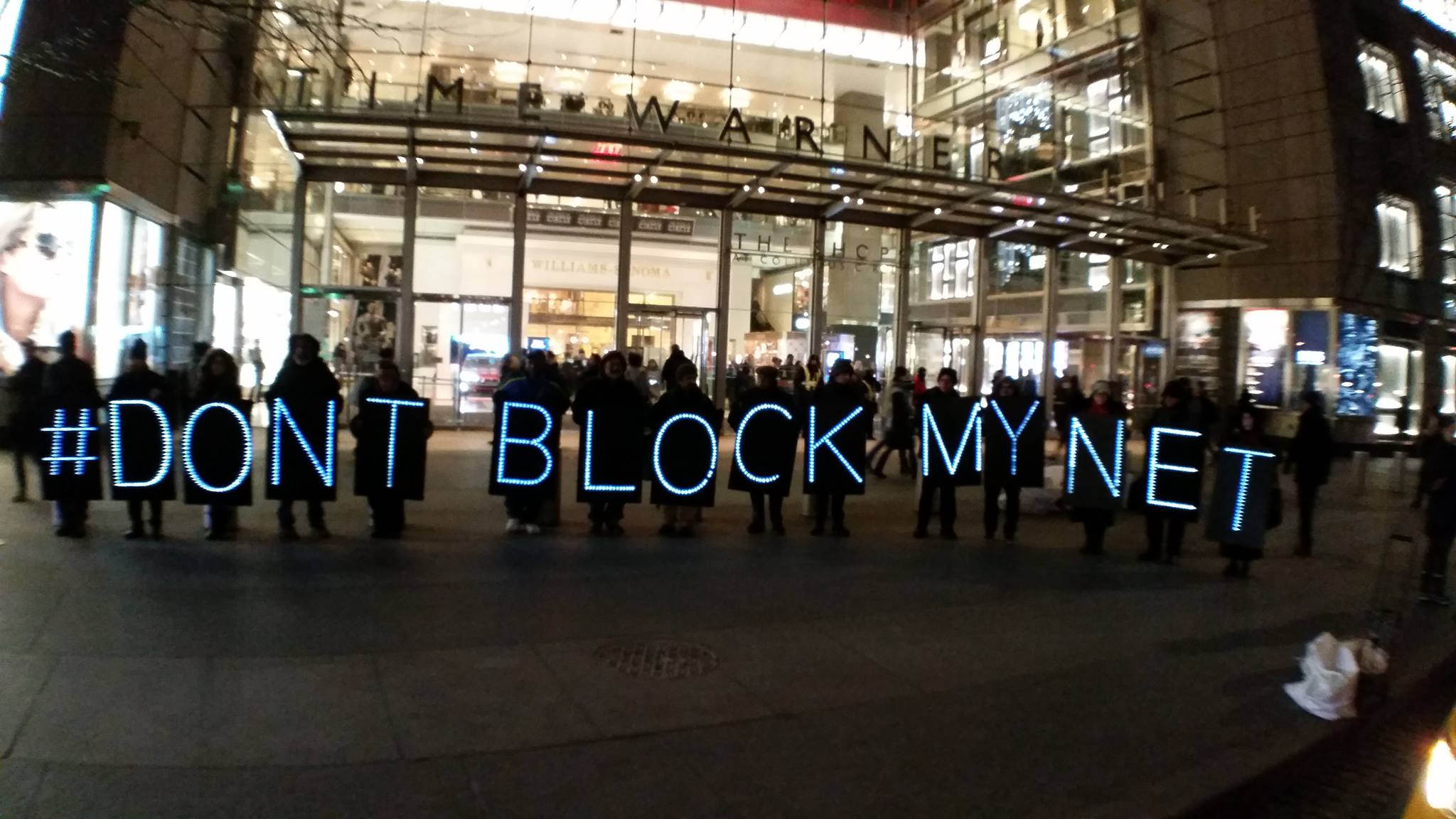 Imagem de um protesto contra a queda da neutralidade de rede. Pessoas segurando placas formando a frase 