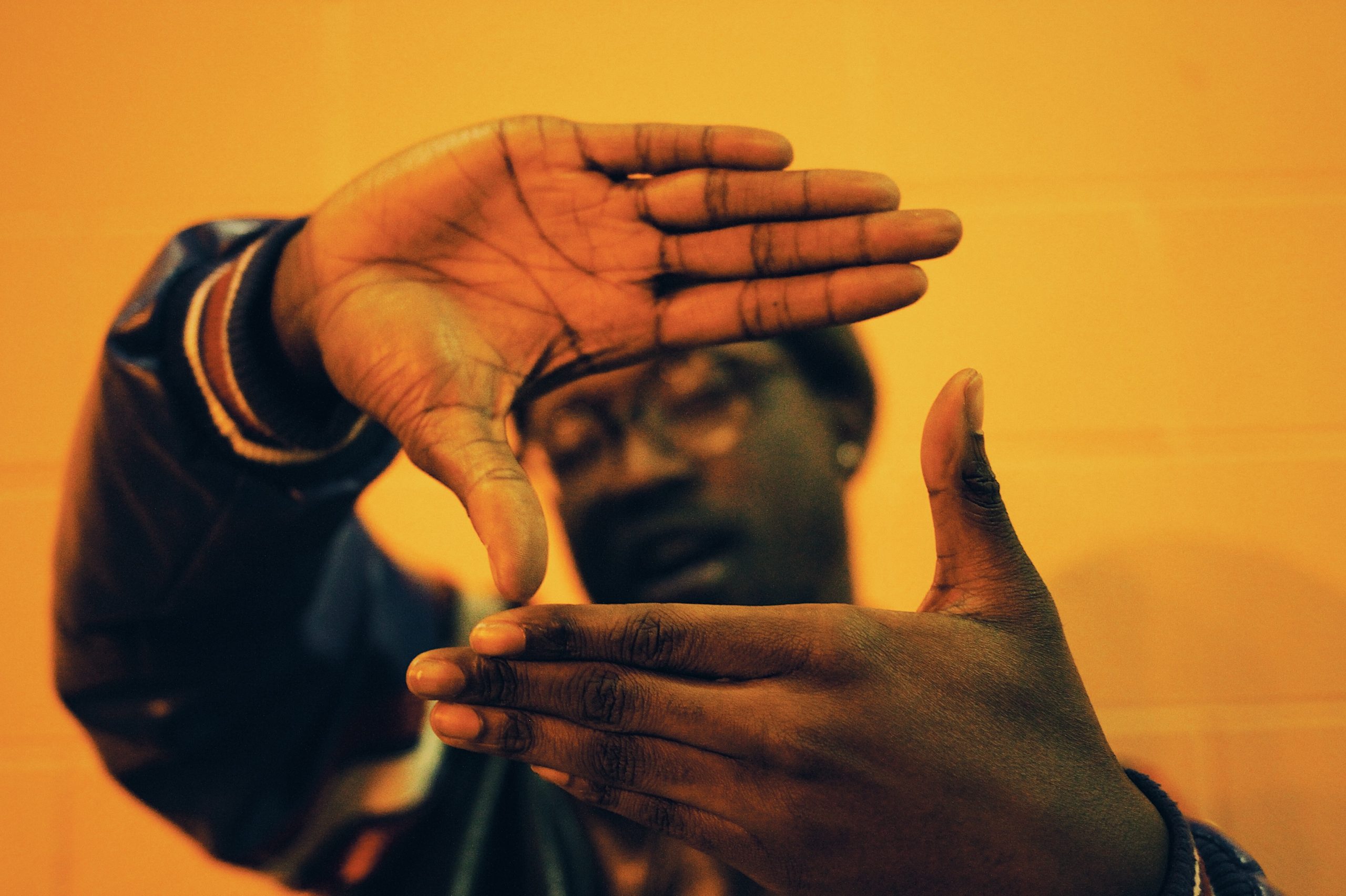 Homem negro fazendo a forma de um retângulo com as mãos